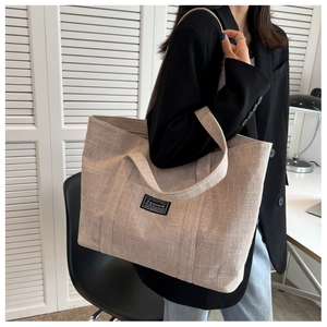Detail of minimalist oatmeal canvas tote bag showing coarse texture and black logo patch