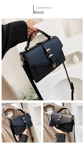 Detail view of black matte leather square bag with golden buckle and crossbody strap