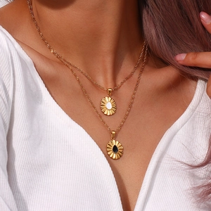 Detail of layered gold necklaces featuring sunburst pendants with black and white stones