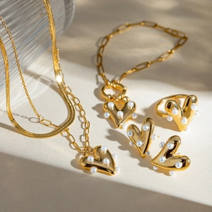 Close-up of gold stainless steel heart jewelry set with elegant white pearl inlay