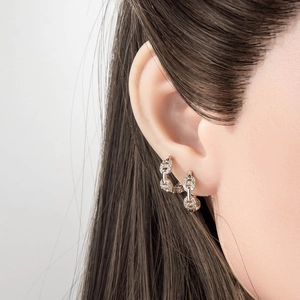 Boucles d'oreilles créoles maillons argentés serties de zircons sur un modèle