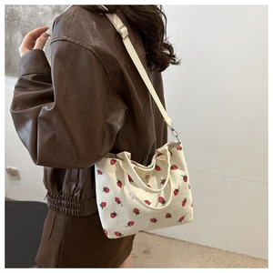 Corduroy tote bag with strawberry print shown on model wearing brown leather jacket