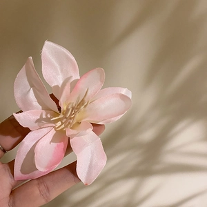 Close-up of pink fabric hibiscus hair clip with realistic petals and stamen detail