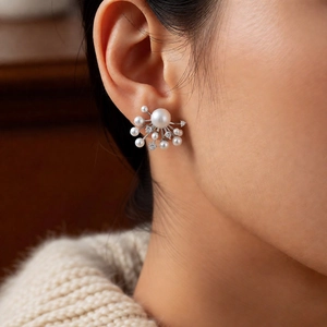 Detailed view of fireworks-inspired pearl and zircon stud earrings worn by a model