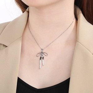 Detail of a silver bow necklace pendant on model with elegant stainless steel finish