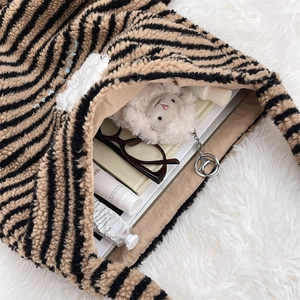 Macro detail of striped plush tote bag showing spacious interior and soft fleece texture