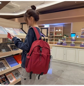 Roter Nylon-Rucksack mit großem Hauptfach und Seitentasche in einer Lifestyle-Umgebung