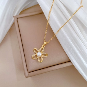 Detailed shot of pearl flower pendant with crystals on gold chain over silk background
