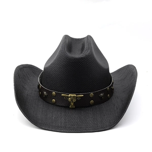 Detail of woven black cowboy hat featuring a leather band and golden bull head emblem