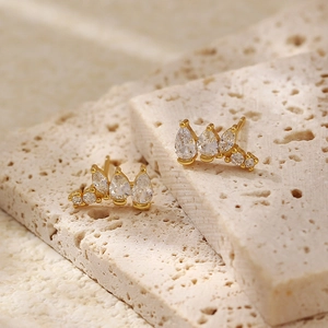 Macro detail of gold stud earrings with irregular pear and round zircon stones