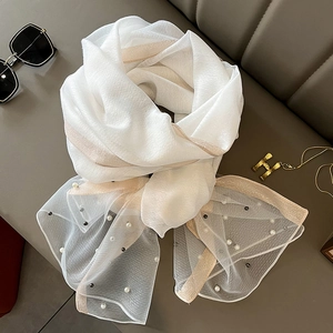 Detail of white silk-like scarf with pearl beads and gold glitter edges on leather