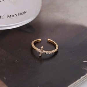 Elegant gold-tone cross ring with micro-p鑲zircon stones on a textured dark background