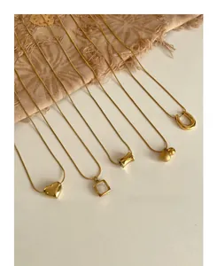 Detail showing various gold-plated titanium steel charms on sleek snake chains