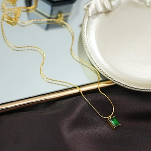 Vintage gold necklace with rectangular emerald pendant on elegant silk background