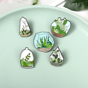 Macro detail of enamel pins set featuring succulent terrariums and cacti in glass jars