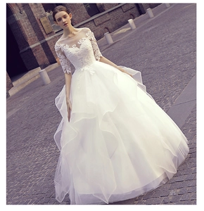 Detail of white bridal gown featuring intricate lace embroidery and multi-layer tulle skirt