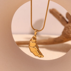 Detail of 18K gold plated horn pendant on a thin snake chain for women with soft lighting