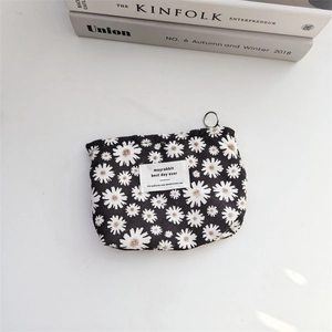 Close-up of black corduroy cosmetic pouch with daisy print and silver metal ring puller