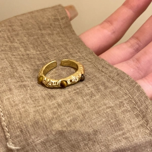Detail of gold-plated tiger eye stone ring with hammered texture on vintage burlap