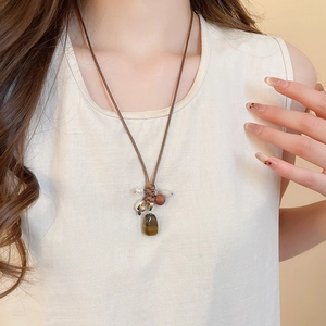 Detail of tiger eye stone pendant and wax rope necklace on a model's neck