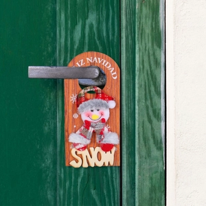 Christmas snowman wooden door hanger sign with SNOW letters hanging on a green door
