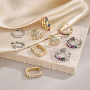 Elegant geometric pearl and zircon earrings displayed on luxury silk and stone texture