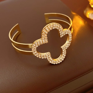 Dettaglio del bracciale aperto a quadrifoglio dorato con cristalli su pelle scura