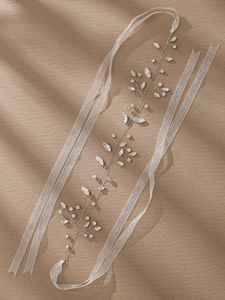 Close-up of bridal headband with silver wire, sparkling rhinestones and white ribbon ties