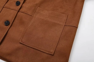Détail d'une veste en daim marron avec grande poche à rabat et bouton noir