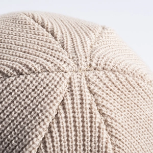 Close-up of beige knit beanie top showing detailed rib knit texture and precision stitching