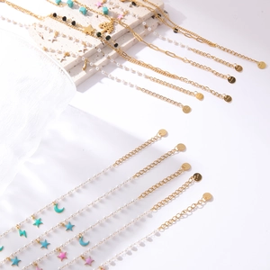 Luxe gold stainless steel pearl bracelet with colorful charms on a white stone background