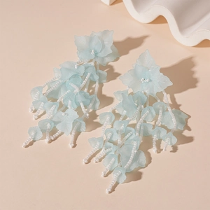 Detail view of light blue and white acrylic leaf tassel earrings with elegant beadwork