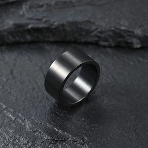 Macro shot of 10mm wide matte black brushed titanium steel ring on dark textured rock