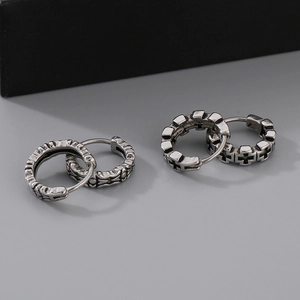 Detail of vintage silver hoop earrings featuring embossed cross and Gothic patterns