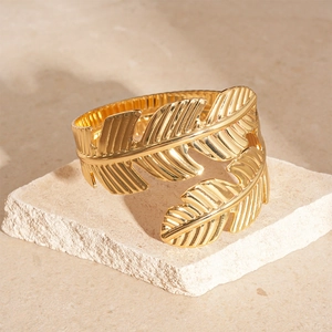 Macro detail of the golden leaf texture on a polished metal open bangle bracelet