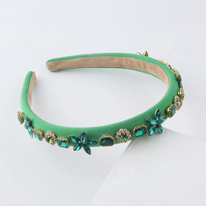 Detail of luxury emerald velvet headband with green crystals and gold accents