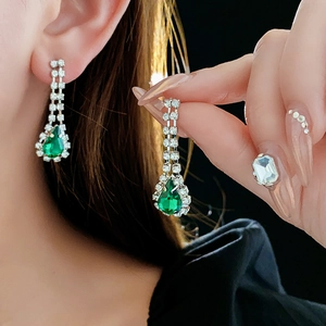 Detail of elegant emerald teardrop earrings with silver metal and sparkling rhinestones