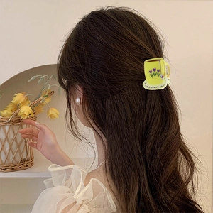 Detail of yellow coffee cup hair claw clip with purple tulip design on a model