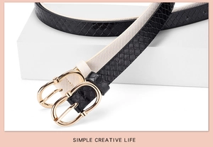 Detailed view of snake skin texture belts in black and cream with gold oval buckles