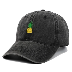 Close-up of yellow pineapple embroidery on vintage washed grey denim baseball cap