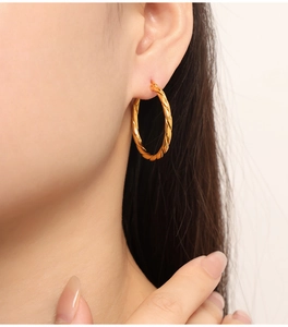 Gros plan de boucles d'oreilles créoles dorées torsadées sur le profil d'un mannequin