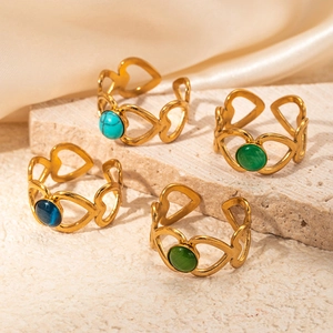 Détail de quatre bagues cœur doré ajouré avec turquoise et pierres précieuses sur soie
