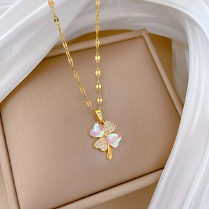 Macro detail of gold clover pendant with iridescent shell petals and sparkling crystals