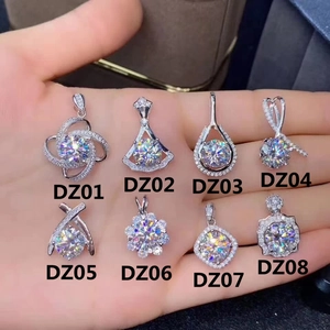 Macro display of eight silver Moissanite pendant designs held in palm showing crystal clarity