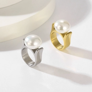 Detail von gold- und silberfarbenen Ringen mit großen Perlen und gebürsteter Metalloberfläche