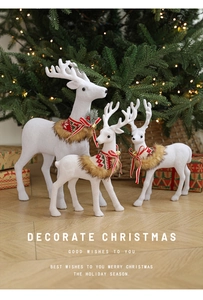 Close-up of white flocked reindeer with red festive scarves and bells for Christmas