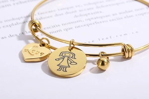 Macro shot of gold stainless steel heart charm with Love engraving and girl charm