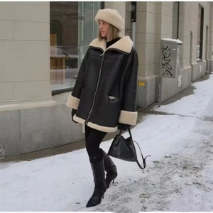 Women's oversized black shearling jacket with faux leather and cream wool lining in snow