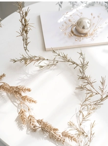 Close-up of glittery golden Christmas branch decoration on a minimalist white surface