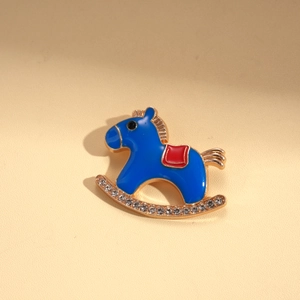 Close-up of blue enamel rocking horse brooch with sparkling rhinestones and golden base